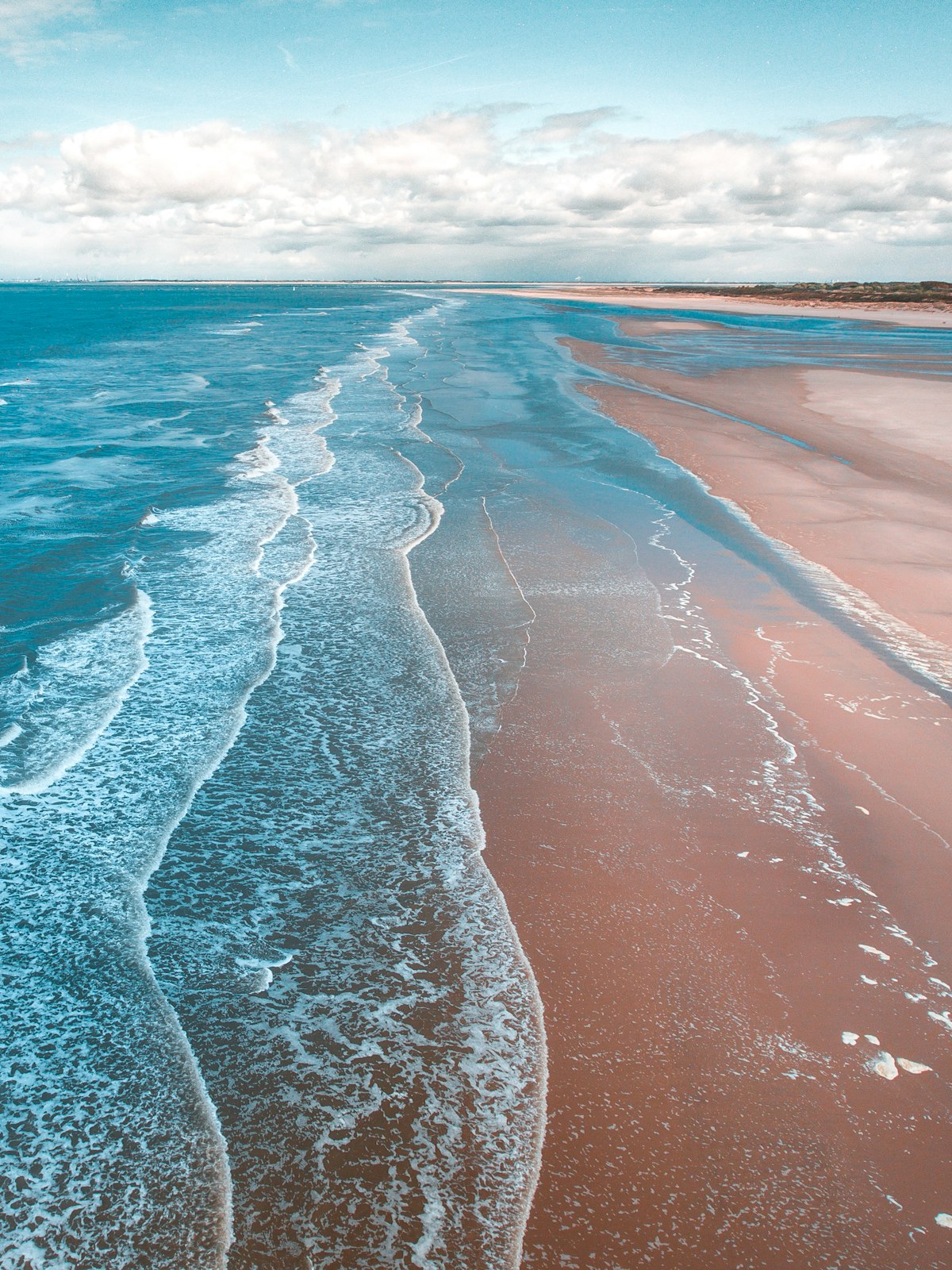 Aerial view of pristine beach shoreline with turquoise waves and tan sand — Labor Day 2026 NRI getaway