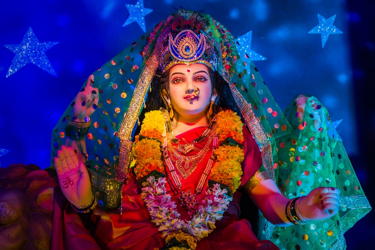 Durga in red and gold sari with elaborate flower arrangements — Durga Puja 2026